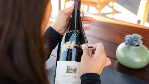 Applying gilding wax on MacRostie wine bottle, while sitting out on the tasting room patio in Healdsburg